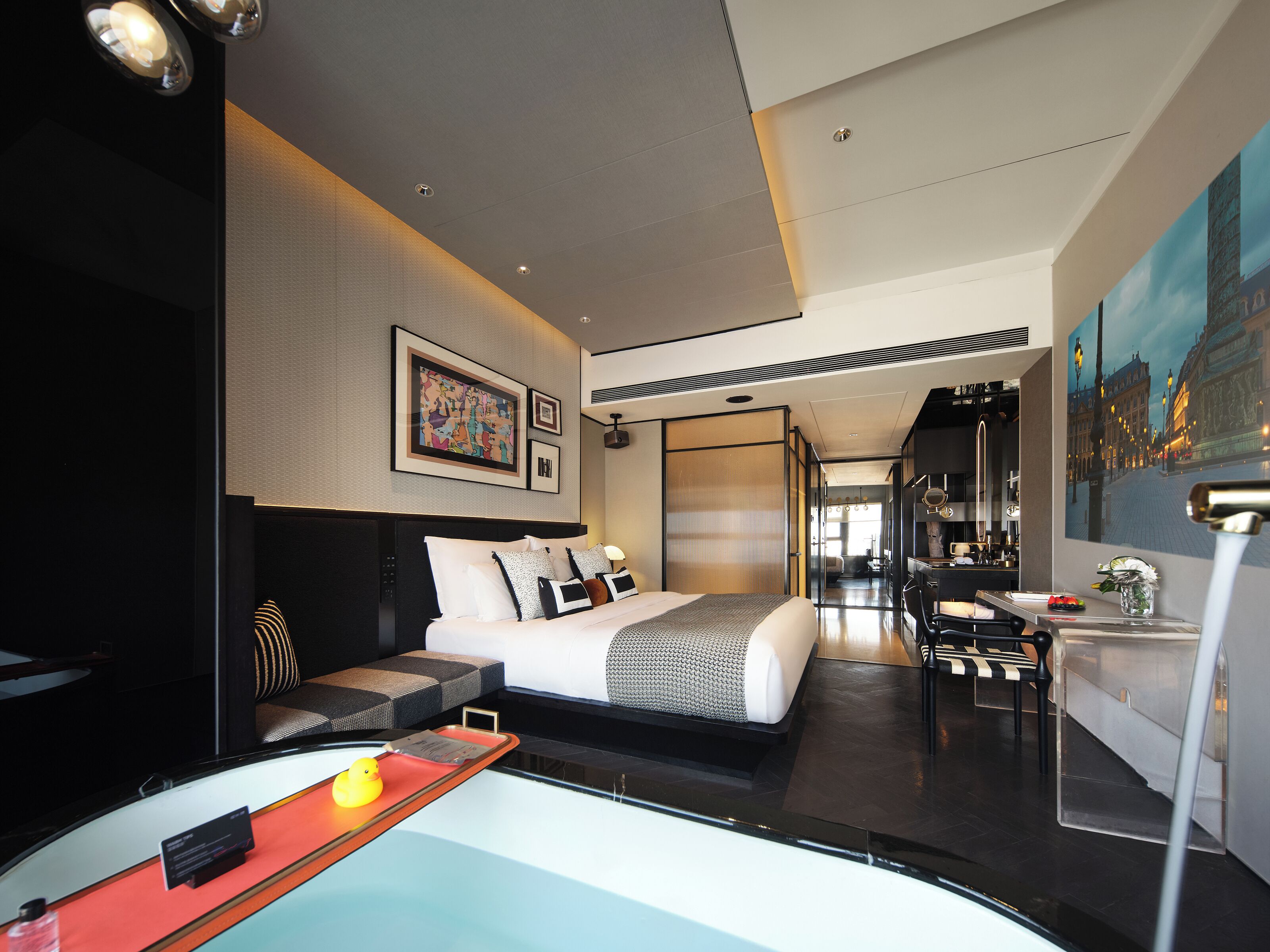 A modern hotel room with a large bed, a desk, and a view of the cityscape.