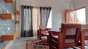 A dining area with a brick wall, wooden shelves, and a patterned rug. - 2 BHK apartment in Hosapete for a relaxing stay (Hosapete)