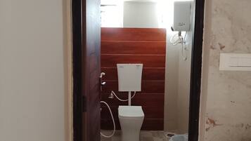 A bathroom with a toilet, a shower, and a water heater.