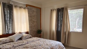 A bedroom with a bed, curtains, a window, and a wall with a textured pattern. - 2 BHK apartment in Hosapete for a relaxing stay (Hosapete)