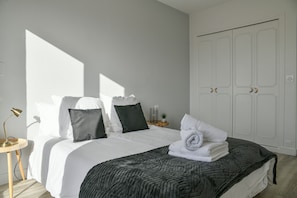 A neatly made bed with pillows, a bedside lamp, and a small plant on a nightstand.
