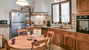 Una cocina con armarios de madera, un refrigerador, una estufa y una mesa de comedor con sillas.