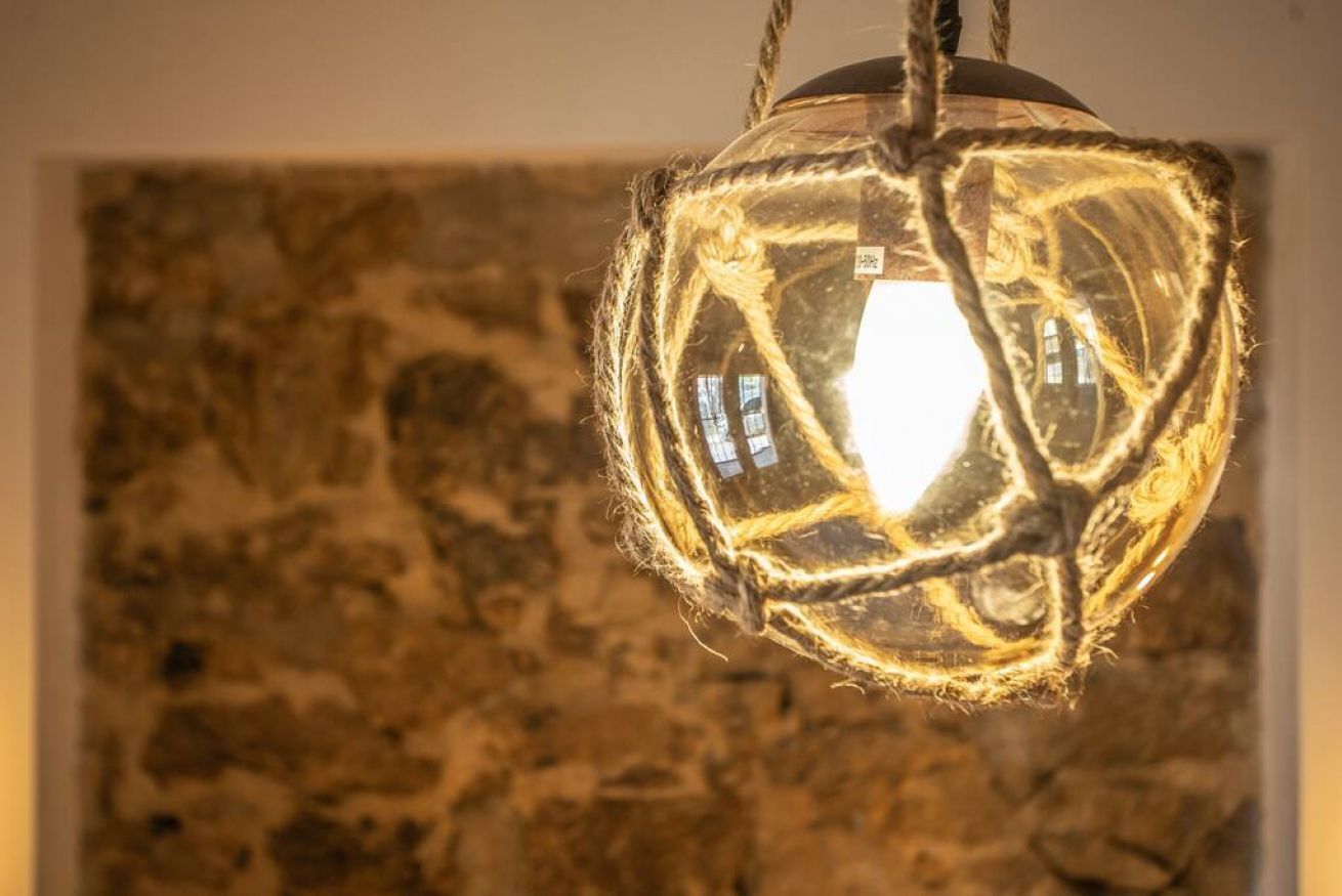 A spherical light fixture with a rope-wrapped design, hanging from a ceiling.