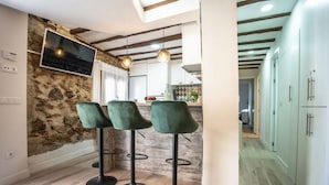 Une cuisine moderne avec des murs en pierre, un téléviseur et des tabourets de bar.