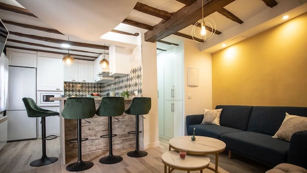 Une cuisine moderne avec des tabourets de bar, une table à manger et un canapé dans l’espace salon.
