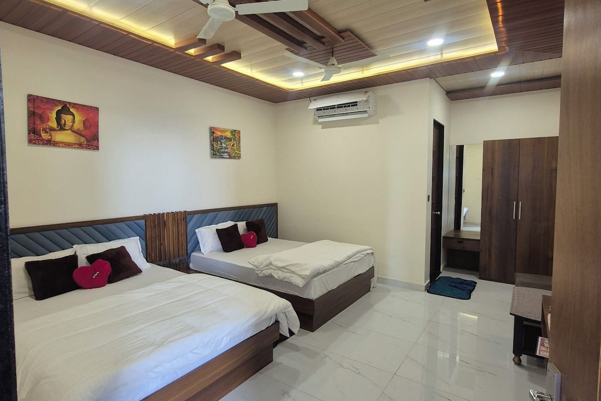A hotel room with two beds, a ceiling fan, an air conditioning unit, and a tiled floor.