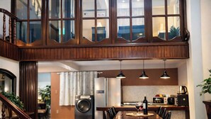 A modern kitchen with a dining area, wooden staircase, and large windows.