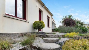 A building with a red door, a small round bush, and a stone staircase leading up to the entrance.