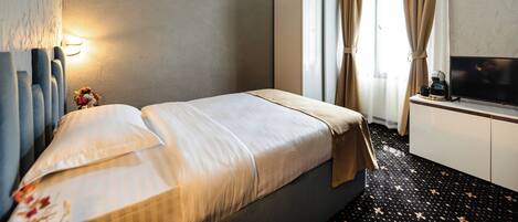 A hotel room with a bed, a TV, a wardrobe, and a desk with a coffee maker.