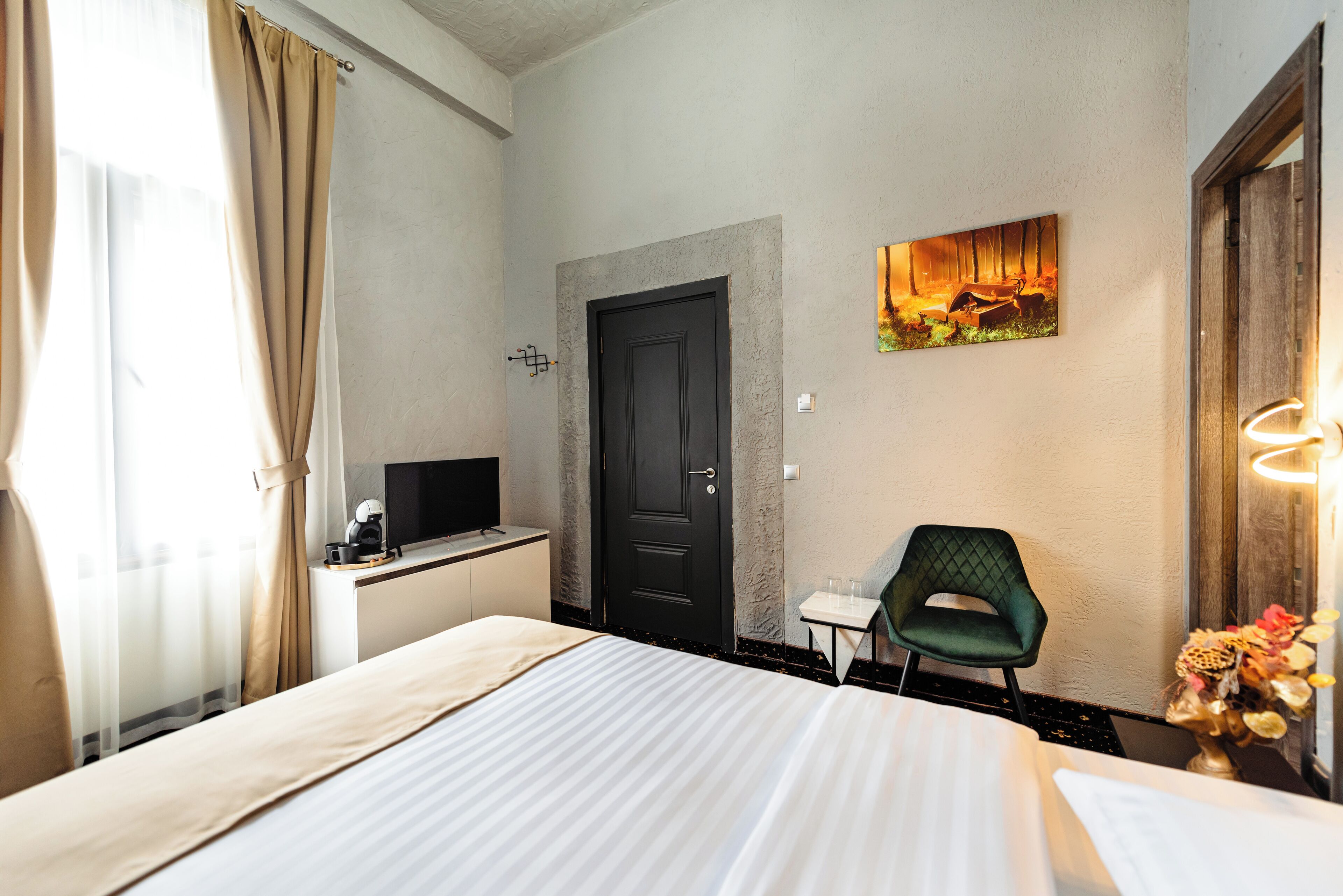 Habitación de hotel con cama, escritorio, computadora, silla y un cuadro en la pared.
