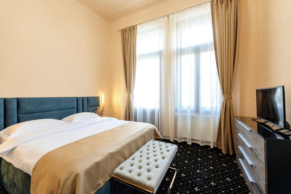 Una habitación de hotel con cama, reposabancos, cómoda y televisor.