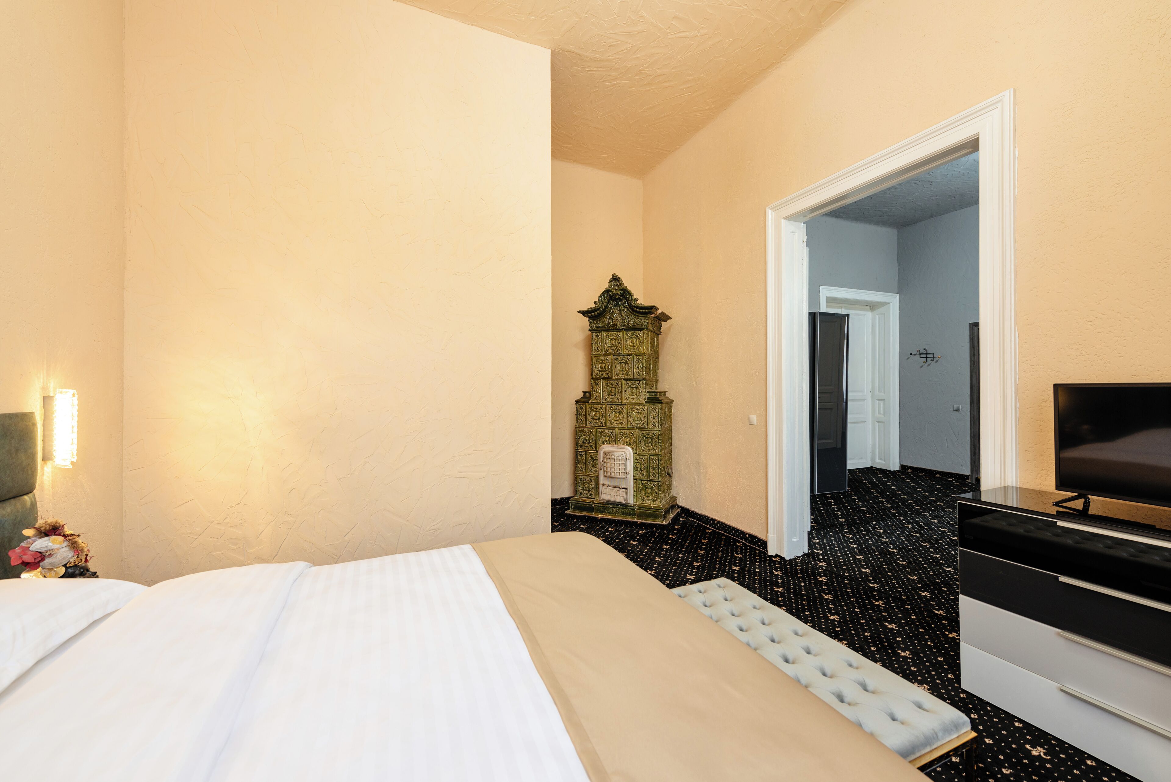 A hotel room with a bed, a dresser, a television, and a decorative cabinet.