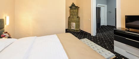 A hotel room with a bed, a dresser, a television, and a decorative cabinet.