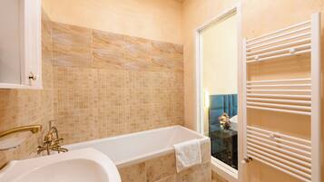 A bathroom with a bathtub, a glass shower enclosure, a towel rack, and a tiled wall.