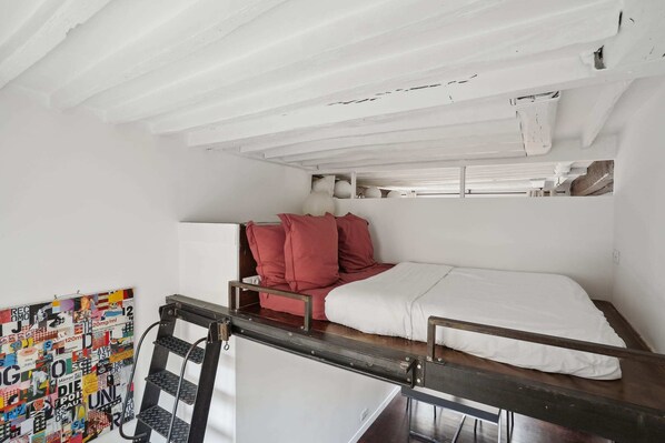 A small, compact room with a bunk bed, a white wall with a colorful poster, and a wooden desk with a chair. - Spacious 2BR in The Heart of Saint Germain (Paris)