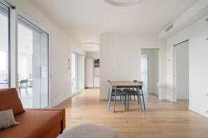 A modern interior with a dining area, a sofa, and a view through large glass doors.