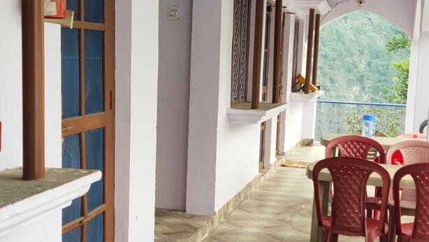 A corridor with patterned flooring, a wooden door, and a table with chairs. - Hotel Shri Ganesh Hari Ganesh (Ukhimath)
