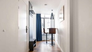 Ein Korridor mit Holzboden, einem blauen Vorhang, einer Bar mit Hockern und einer Pendelleuchte.