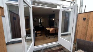 Eine geöffnete Schiebetür, die in einen Raum mit Esstisch und Stühlen, einer Lampe und einer Deckenleuchte führt.