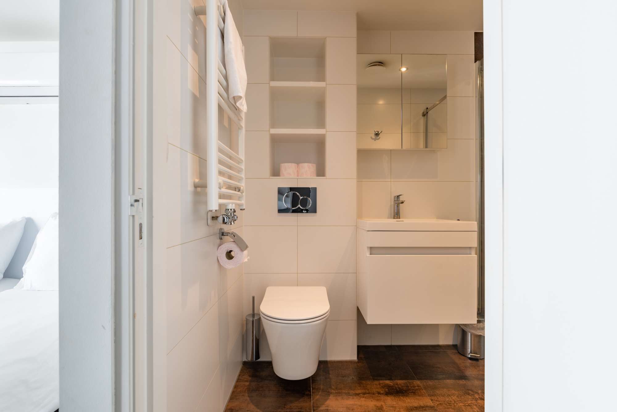 Un baño moderno con inodoro, lavamanos y perchero para toallas.