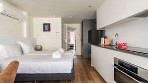 Una camera d'albergo moderna con un letto, angolo cottura e televisione.