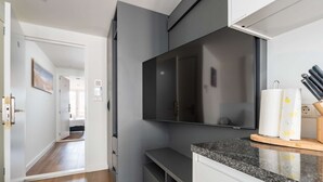 Una cucina moderna con un ampio televisore a schermo piatto, un piano di lavoro in granito e un tagliere in legno.