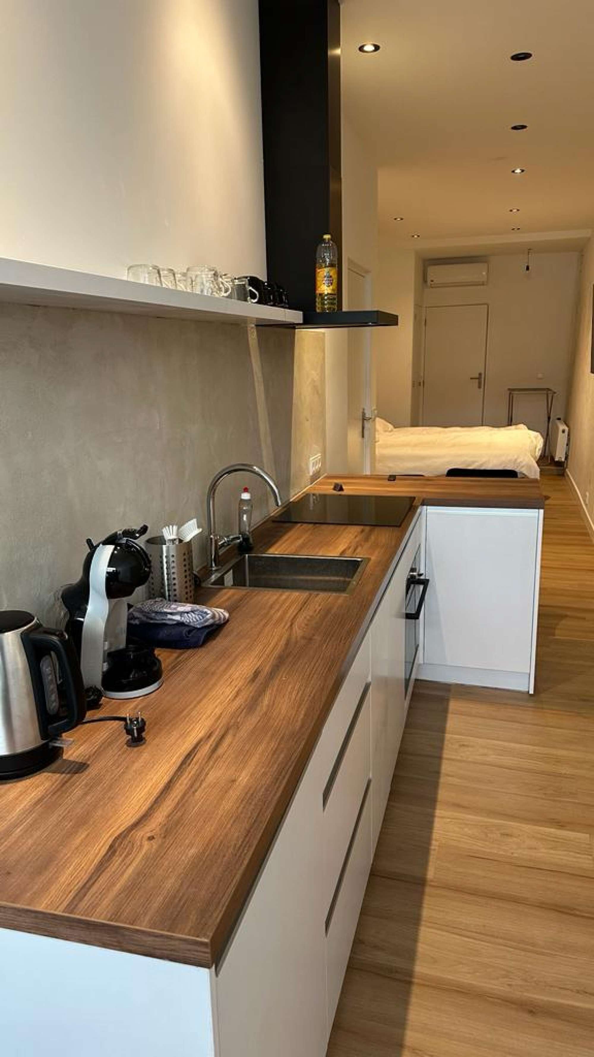 Eine moderne Küche mit Holztischplatte, Spüle und einem kompakten Kühlschrank.