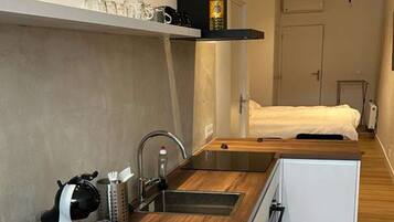 Eine moderne Küche mit Holztischplatte, Spüle und einem kompakten Kühlschrank.