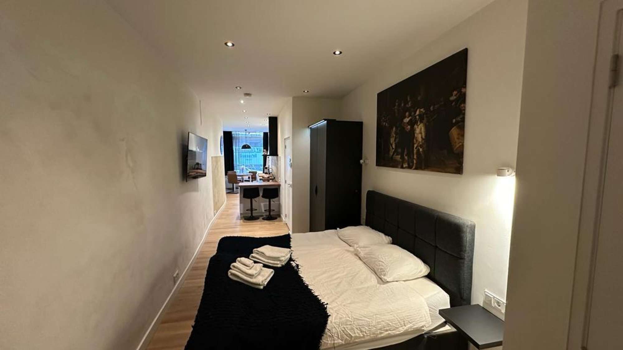 Un pasillo estrecho que conduce a un dormitorio con cama, escritorio y silla.