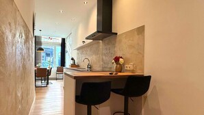 Una cocina moderna con una isla central, dos taburetes de bar y vistas al comedor.
