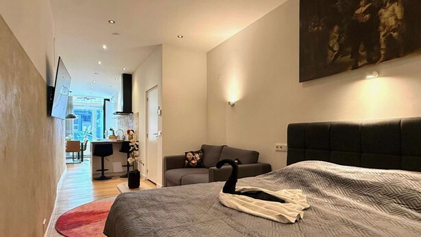 Ein modernes Hotelzimmer mit einem großen Bett, einer Couch, einem Essbereich und Blick auf die Stadt.