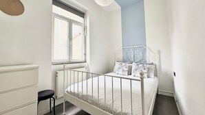 A bedroom with a white bed, a window, a radiator, and a chair. - Cozy 3-bedroom apartment with AC, Sauna close to Galataport , Taksim (Istanbul)