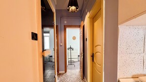 A narrow hallway with patterned floor tiles, a wooden door, and a hanging light fixture. - Cozy 3-bedroom apartment with AC, Sauna close to Galataport , Taksim (Istanbul)