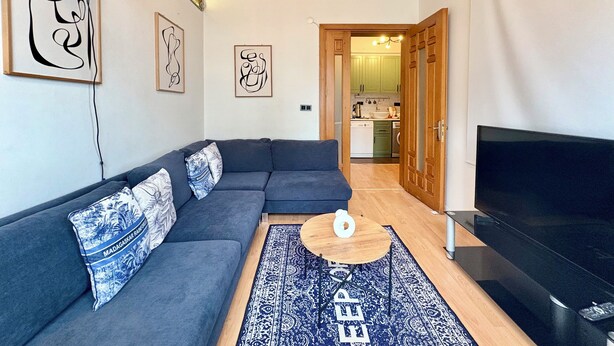 A modern living room with a grey sofa, a flat-screen TV, and a wooden coffee table. - Cozy 3-bedroom apartment with AC, Sauna close to Galataport , Taksim (Istanbul)