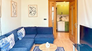 A living room with a dark blue sofa, two wall-mounted abstract art pieces, a wooden coffee table, and a TV on a stand. - Cozy 3-bedroom apartment with AC, Sauna close to Galataport , Taksim (Istanbul)