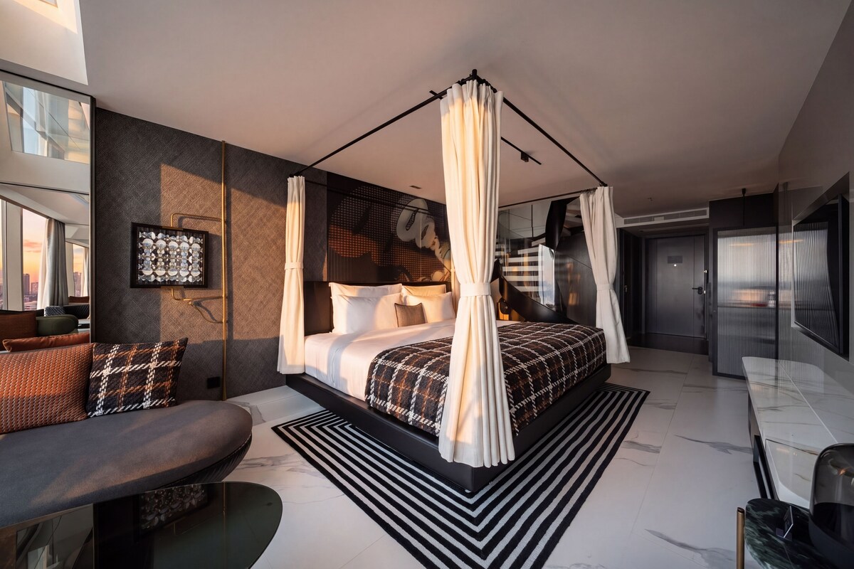 Een moderne slaapkamer met een bed, een zithoek en een groot raam.