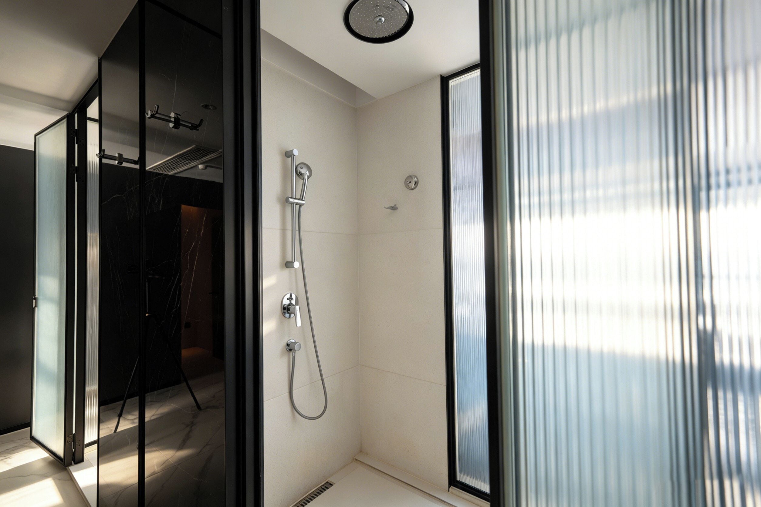 Un baño moderno con cabina de ducha de vidrio, ducha visible y ventilación en el techo.