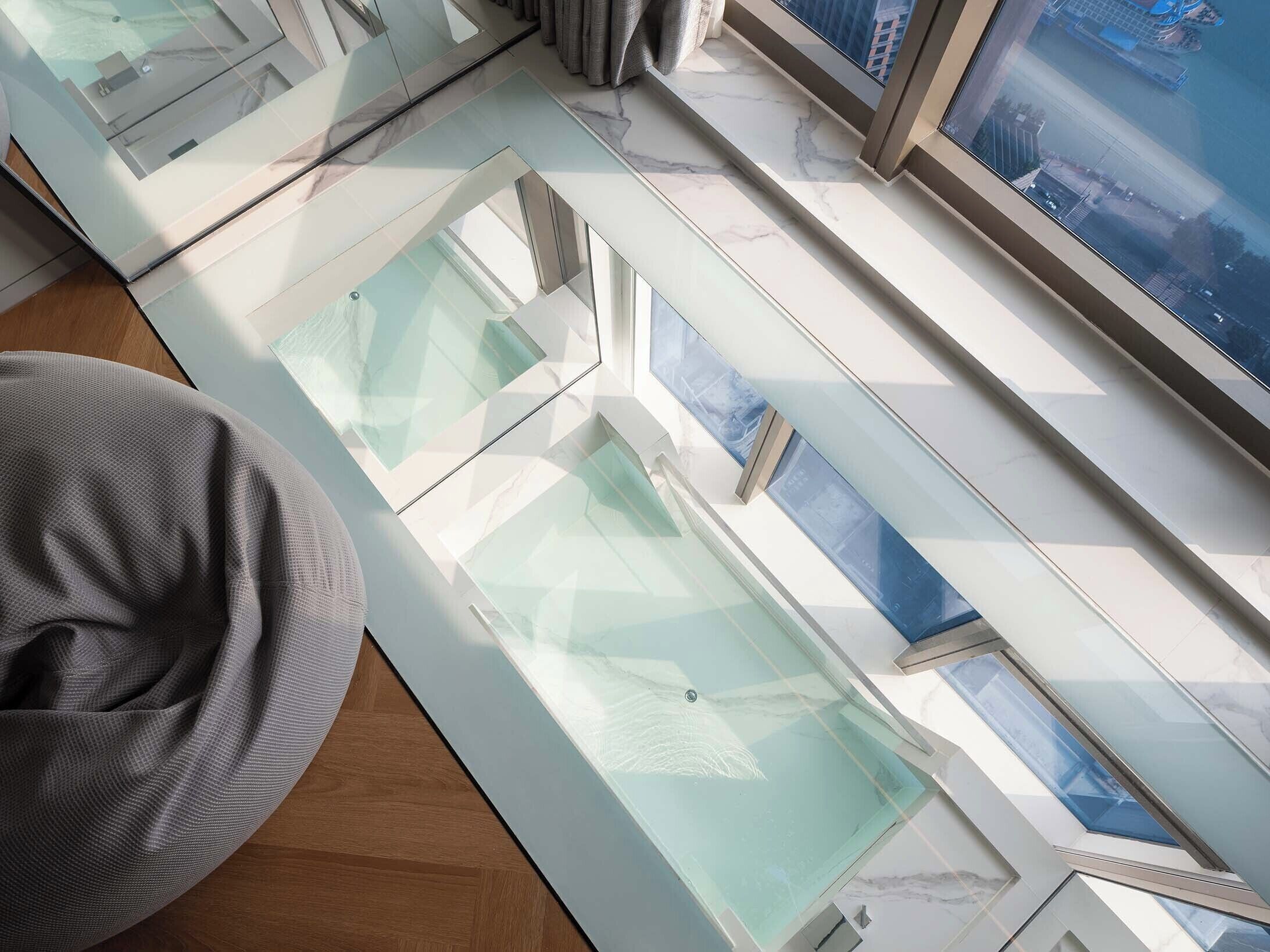 Ein modernes Interieur mit Glasdecke, grauem Sitzsack und Blick auf die Stadtlandschaft.