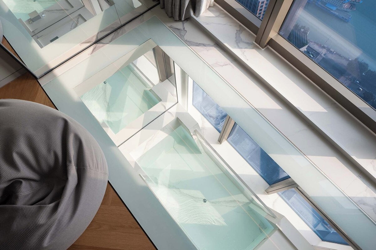 Een modern interieur met een glazen dak, een grijze kruikzak en uitzicht op de stad.