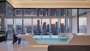 Un salon moderne avec vue sur la ville, une piscine à débordement et un plafond haut.