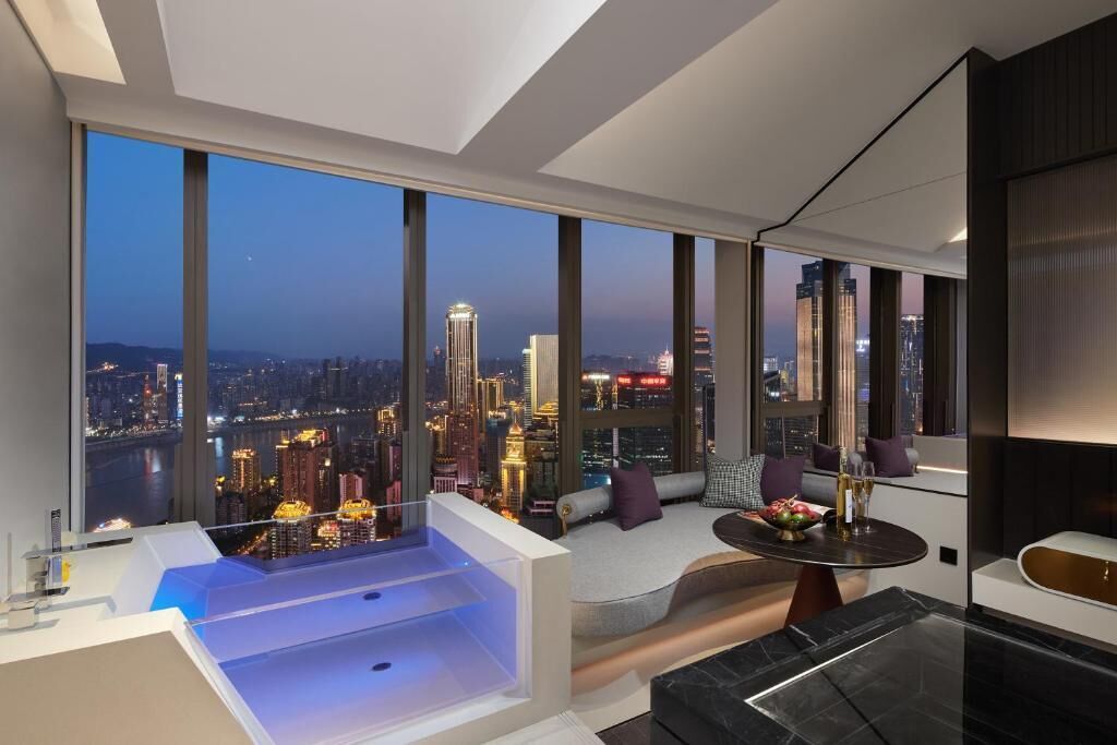 Una habitación moderna con vista a la ciudad, una bañera, un sofá y una mesa de comedor.
