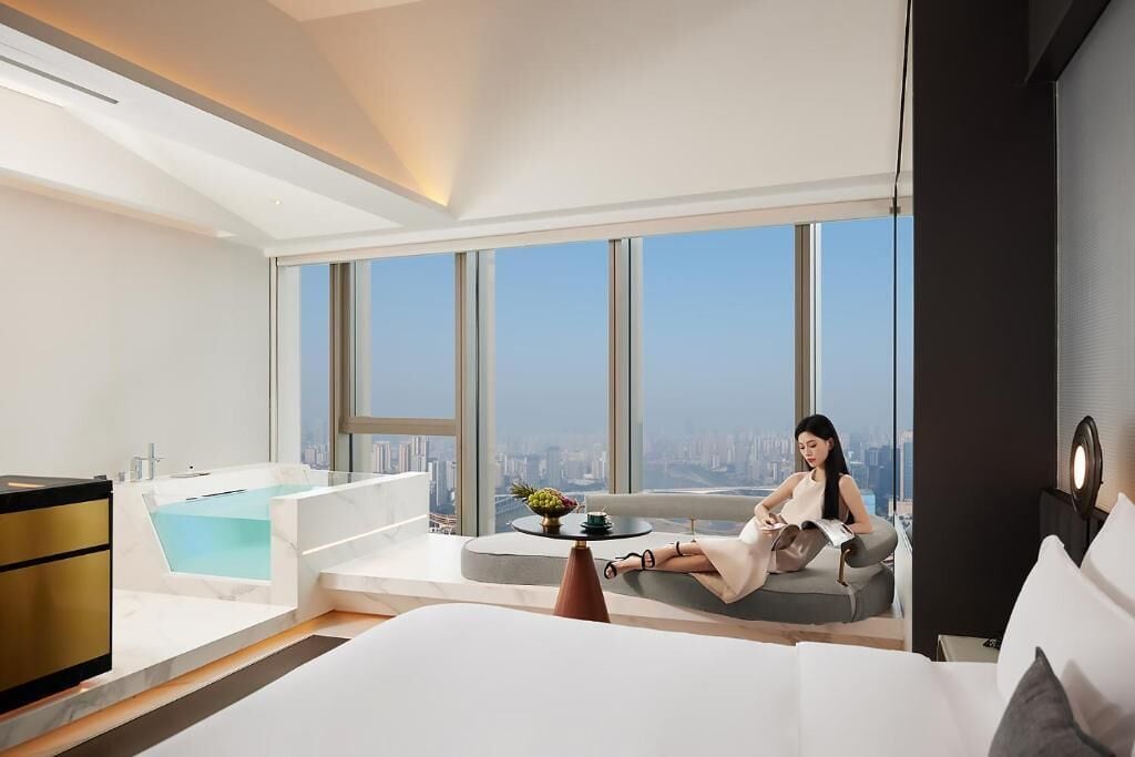 Ein modernes Hotelzimmer mit einem großen Bett, einer Sitzecke mit Blick und einer Badewanne.