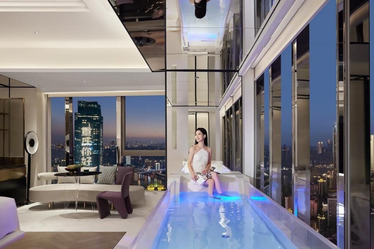 Een modern interieur met een glazen oneindigheidszwembad, uitzicht over de stad en eigentijdse meubels.