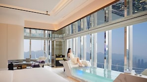 Ein modernes Hotelzimmer mit einem großen Glasfenster, einem privaten Balkon und Blick auf die Stadt.