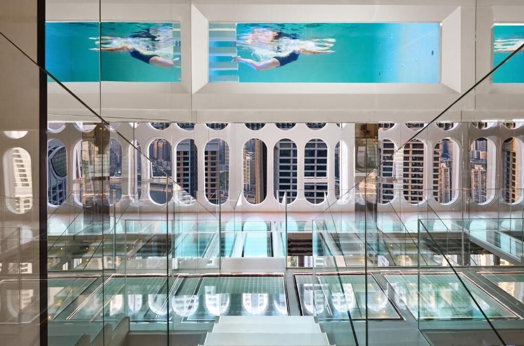 Un intérieur moderne avec une balustrade en verre, une vue sur la ville et une piscine avec un plongeoir.