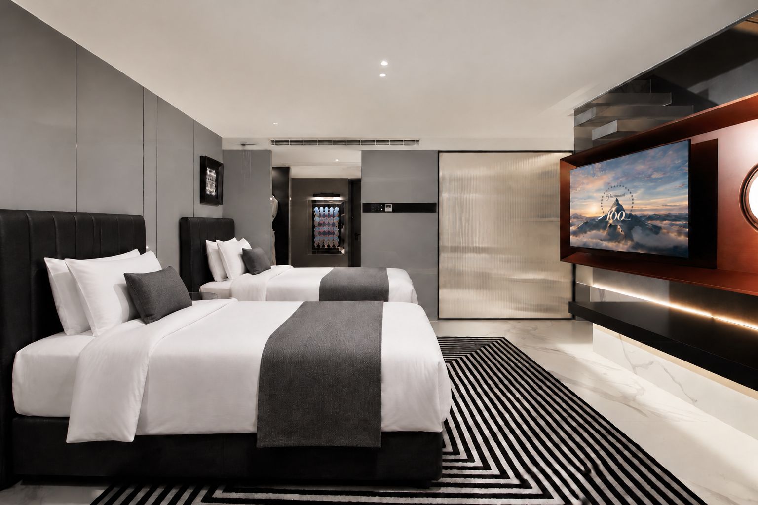 Habitación de hotel moderna con una cama grande, televisión y vistas a las montañas.