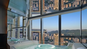 Ein modernes Badezimmer mit einer großen Badewanne, einem gläsernen Fenster und Blick auf eine Stadtlandschaft.