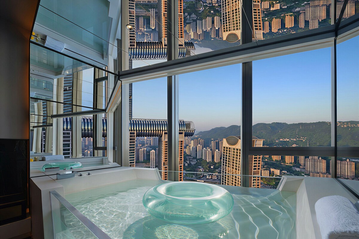 Une salle de bain moderne avec une grande baignoire, une fenêtre à encadrement de verre et une vue sur le paysage urbain.