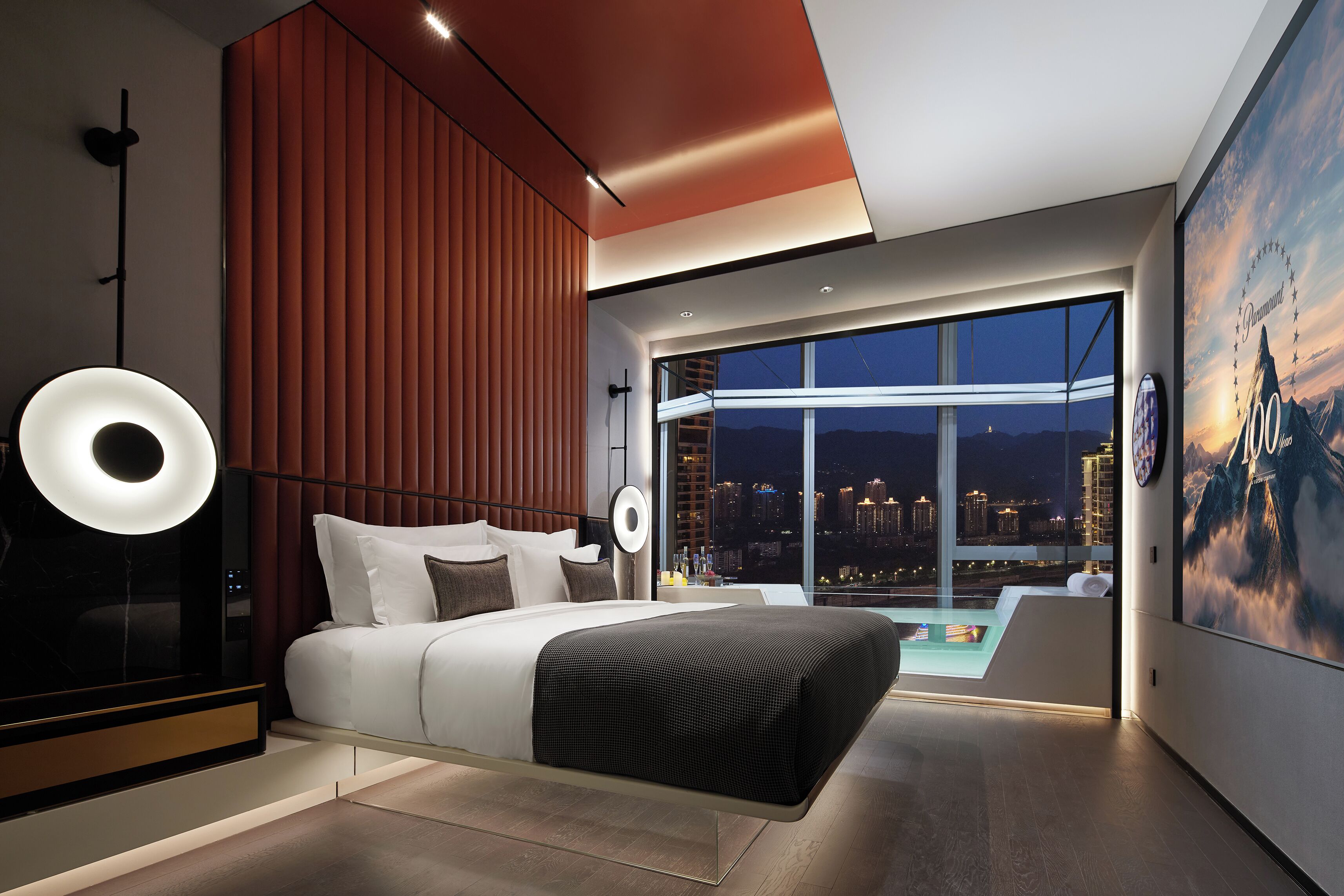 Un dormitorio moderno con una cama, un ventanal grande y vistas a la ciudad.