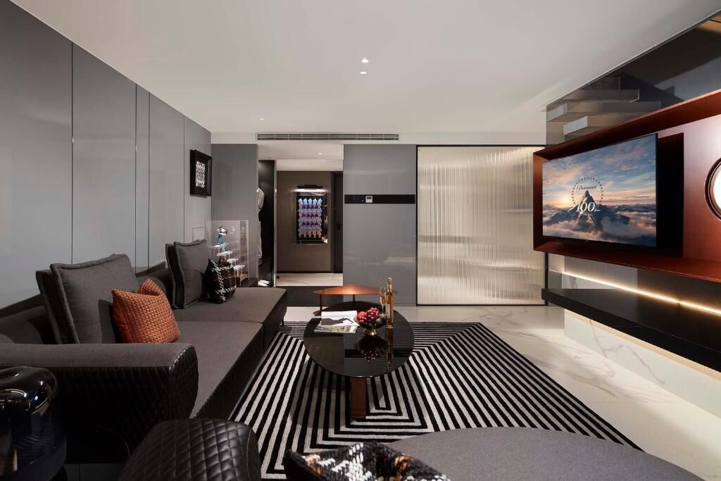 A modern living room with a sofa, a coffee table, and a TV mounted on the wall.